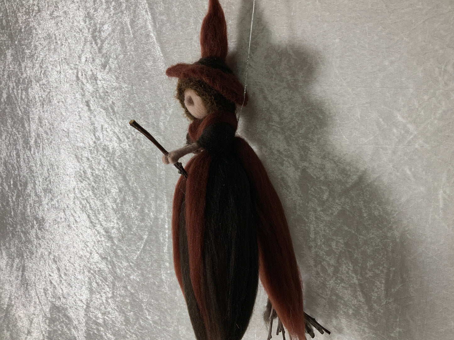 Braune Hexe aus Merinowolle auf einem Besen