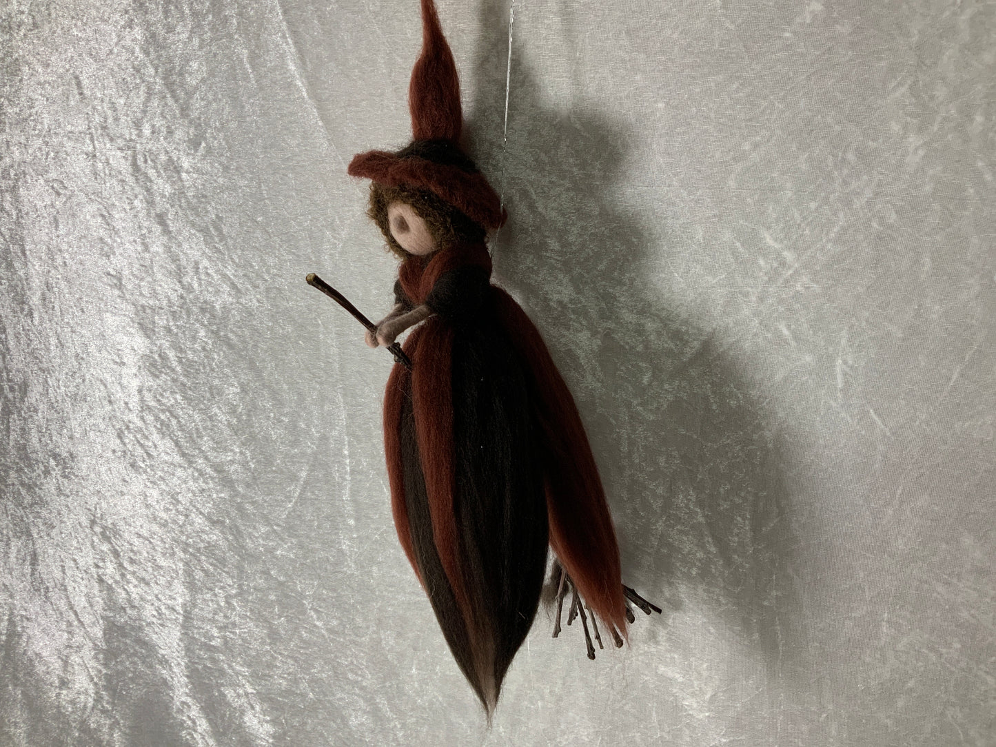 Braune Hexe aus Merinowolle auf einem Besen