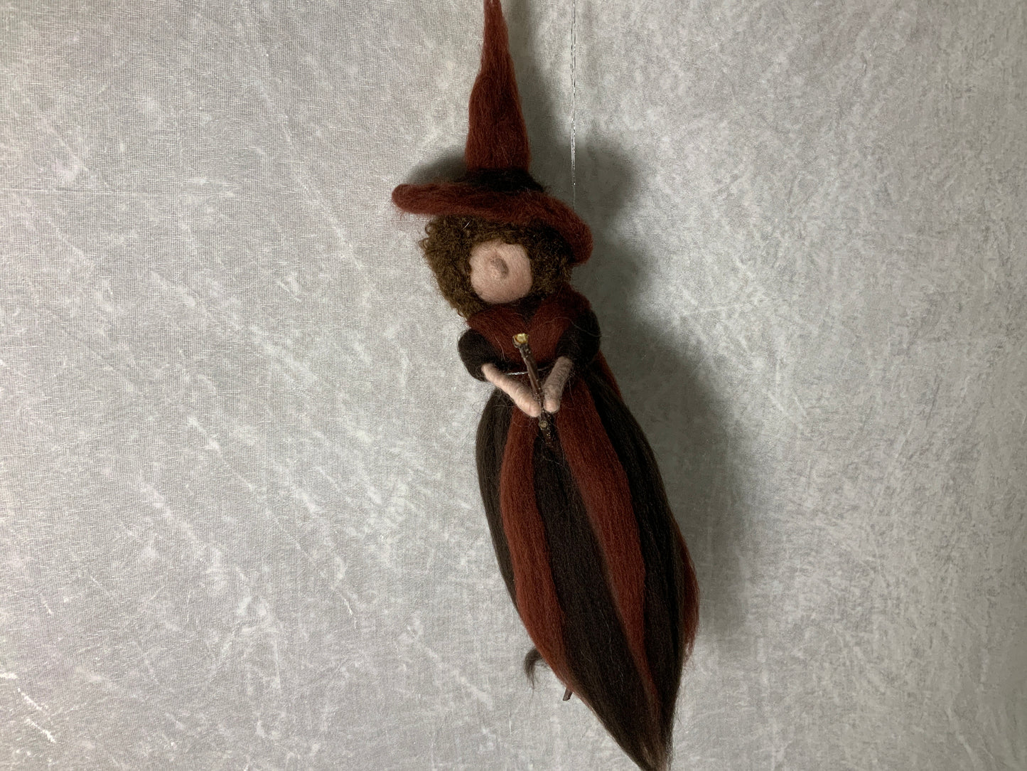Braune Hexe aus Merinowolle auf einem Besen