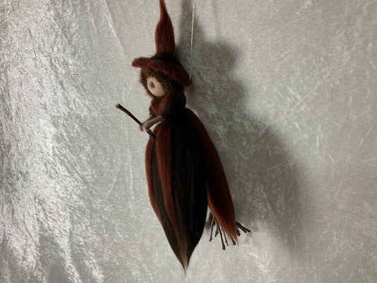 Braune Hexe aus Merinowolle auf einem Besen